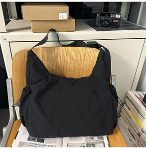 Detail of black nylon crescent hobo bag hanging on a chair showing smooth soft texture