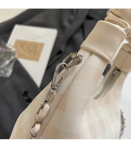 Detail of silver chain link and cloud-style pleated strap on checkered crossbody bag
