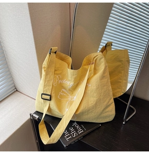 Detail of yellow canvas tote bag with bow print and adjustable black strap buckle