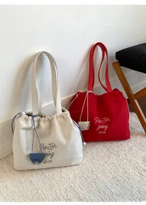 Detail of drawstring canvas tote bags with Pan-Tor embroidery in white and red colors