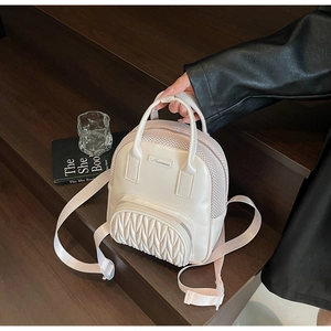 Detail of cream white mini backpack showing quilted front pocket and mesh texture