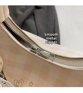 Detail of high-quality smooth silver hardware zipper on checkered cream crossbody bag