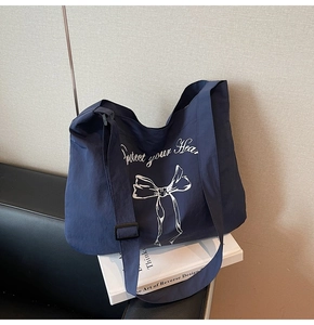 Detail of navy blue canvas tote bag featuring bow print and adjustable strap buckle