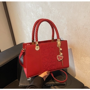 Detail of red wedding handbag featuring floral embossing and a gold Xi character charm