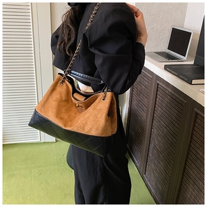 Détail d'un sac cabas en daim marron et cuir matelassé noir avec bandoulière en chaîne