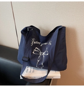 Detail view of deep blue canvas tote bag showing the bow print and adjustable strap