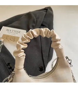 Detail of checkered cream dumpling bag with cloud pleated handle and silver chain strap
