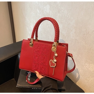 Detail of red bridal handbag featuring floral embossing and woven leather handle