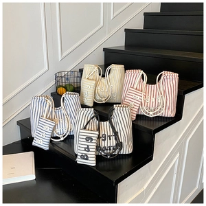 Detailed view of striped canvas tote bags in four colors with thick rope handles and embroidery