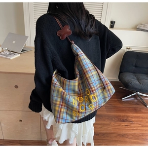 Détail du sac bandoulière en toile à carreaux avec broderie et pendentif en os