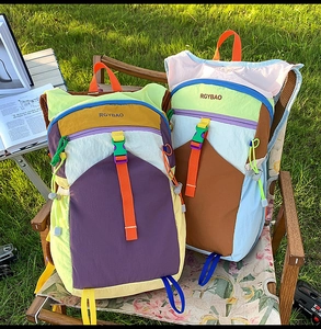 Detail of color-block nylon backpack with buckle straps in an outdoor camping setting
