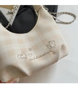 Detailed close-up of checkered fabric texture and bear embroidery on the crossbody bag