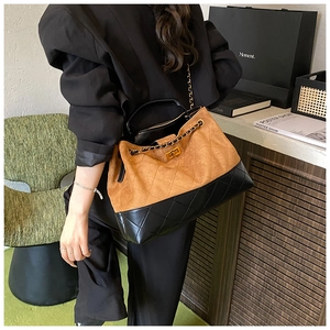 Détail macro du grand sac hobo en daim marron et cuir matelassé noir avec chaîne