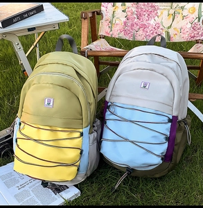 Détail de sacs à dos colorés avec cordons élastiques croisés sur une pelouse verte