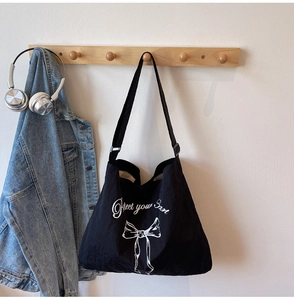 Detail of a large black canvas tote bag featuring Protect your heart text and bow print