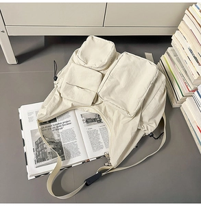 Detail view of cream nylon messenger bag with multiple utility pockets and adjustable strap