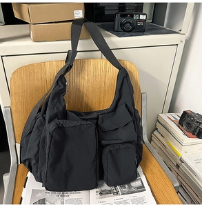 Detail of black multi-pocket crossbody bag hanging on chair in city utility style