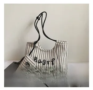 Detail of black and white striped canvas tote with embroidered letters and small pouch