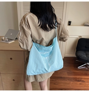 Detail view of light blue canvas tote bag with bow design worn by a model