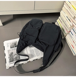 Detail of black tactical messenger bag with multiple utility pockets and nylon texture