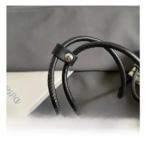 Macro shot of black leather cylindrical handles with silver metallic snap buttons details