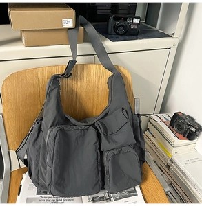 Detailed view of dark grey nylon crossbody bag with multi-pocket utility design