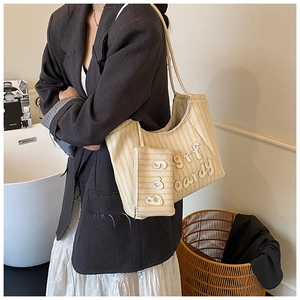 Detail of yellow and white striped tote bag with matching pouch on a fashion model
