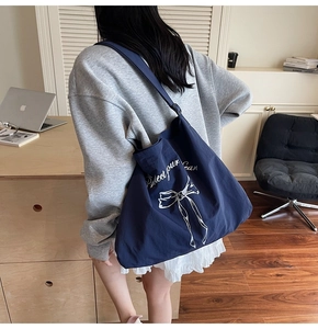 Detail of navy canvas tote bag with white ribbon print and soft adjustable shoulder strap