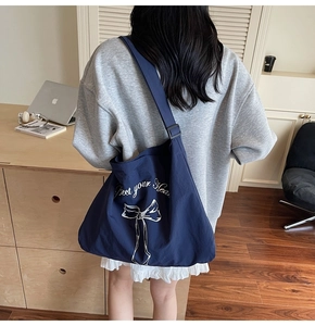 Detail of navy canvas tote bag with bow print and adjustable shoulder strap