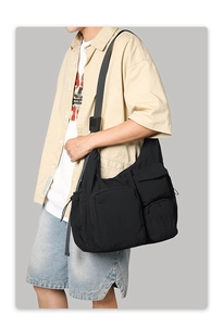 Detail view of black functional multi-pocket messenger bag with wide shoulder strap