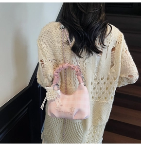 Detail of pink plaid crescent bag with heart embroidery and pearl bow charm