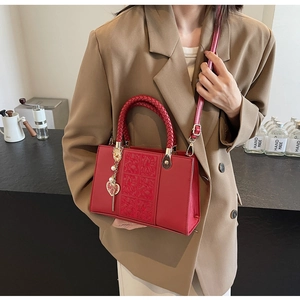 Close-up of vintage red embossed leather bag with woven handle and metal heart charm