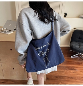 Detail of navy blue canvas tote bag with white bow print and comfortable wide shoulder strap