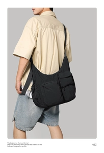 Detail of black nylon messenger bag featuring multiple front pockets and crossbody strap