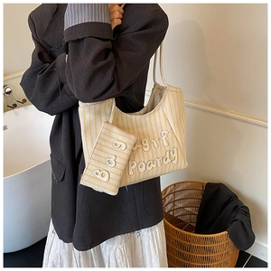 Close-up of yellow and white striped knit tote with 3D embroidery and matching small pouch