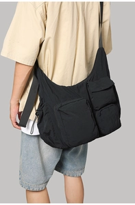 Detail of black multi-pocket crossbody bag with adjustable wide strap and nylon texture