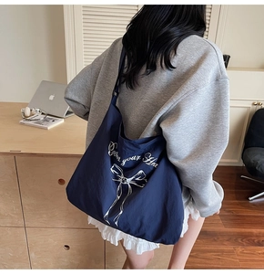 Detail of navy blue canvas tote bag featuring white bow design and lettering
