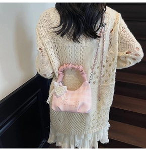 Detailed close-up of pink checkered crossbody bag with pearl heart charm and lace bow