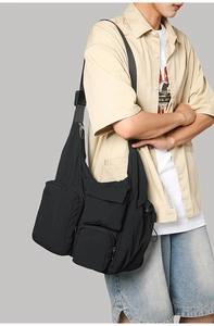 Detail of adjustable woven shoulder strap and side buckles on black nylon messenger bag