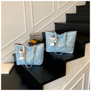 Close-up of light blue woven tote bag with a cute bear pendant on a black staircase