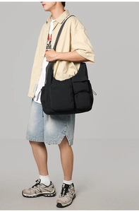 Detail shot of a black functional crossbody bag with multiple pockets and nylon texture