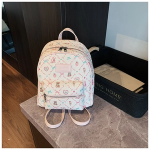 Detailed close-up of cream PU leather mini backpack with cute cartoon bear and heart prints
