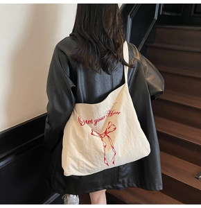 Detail of canvas tote bag featuring Protect your Heart text and red ribbon bow graphic