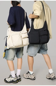 Macro detail of multi-pocket canvas messenger bags in cream and black utility style