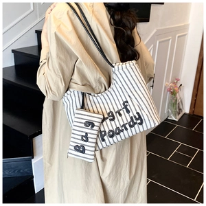 Detail of striped canvas tote bag with embroidered letters and matching zipper pouch
