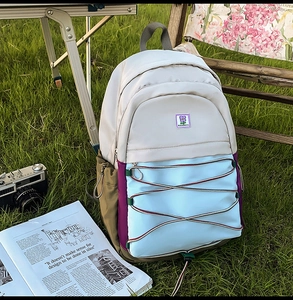 Photo lifestyle d'un sac à dos coloré en nylon sur l'herbe avec accessoires de camping