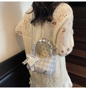 Detail of grey plaid crossbody bag with pearl heart charm and silver metal handle