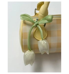 Détail du sac cylindre à carreaux jaunes avec ruban vert et pendentif tulipe