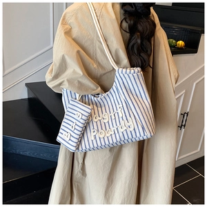 Detail of blue striped canvas tote bag and matching coin purse on a fashion model