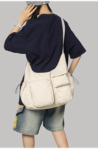 Detailed view of the multi-pocket cream utility crossbody bag with functional zippers